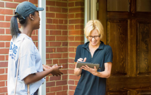 A canvasser interviewing another person at their front door.