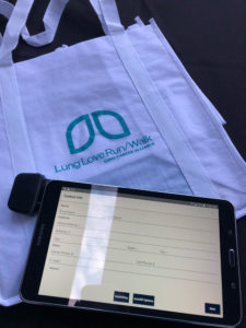 Tote bag that reads Lung Love Run/Walk and has a Grassroots Unwired Android tablet on top of it